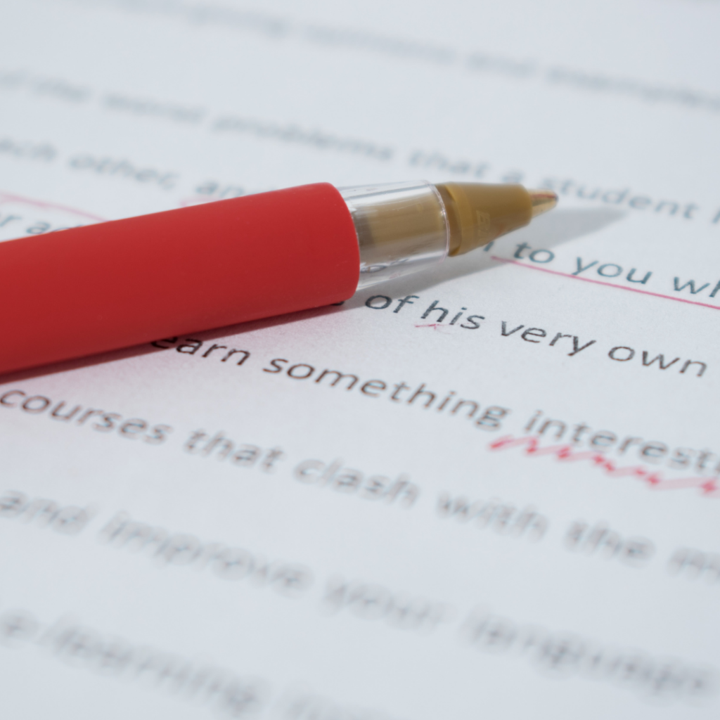 A red ink pen lies on a typewritten sheet of paper.